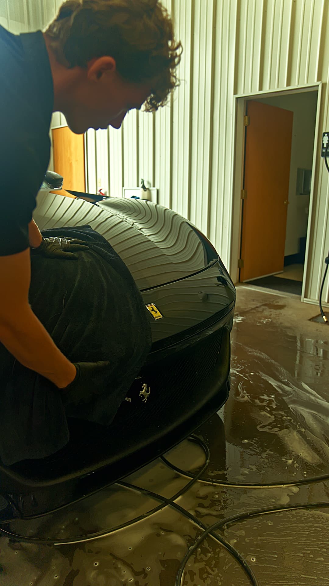 Technician hand-drying a Ferrari in the Brakeout Auto bay