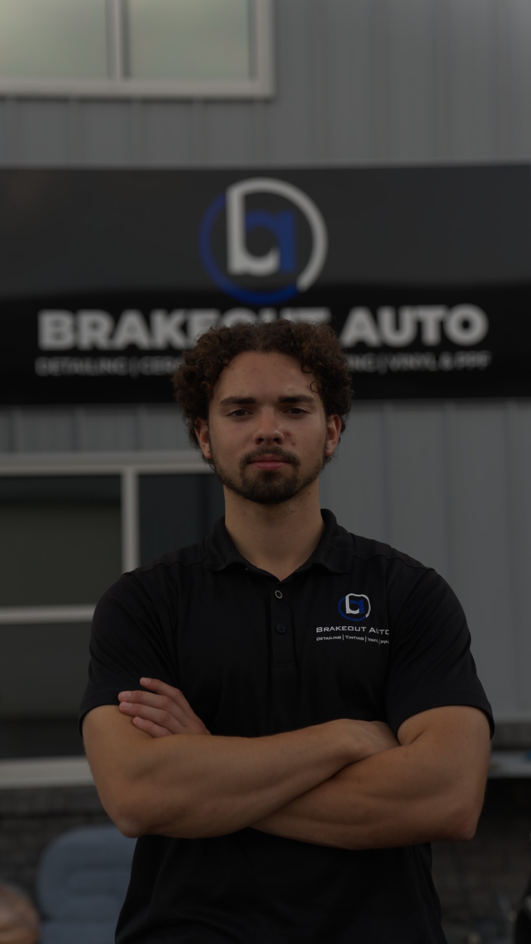 Everett Barter, co-founder and owner of Brakeout Auto, standing in front of the Brakeout Auto shop banner in State College, PA.