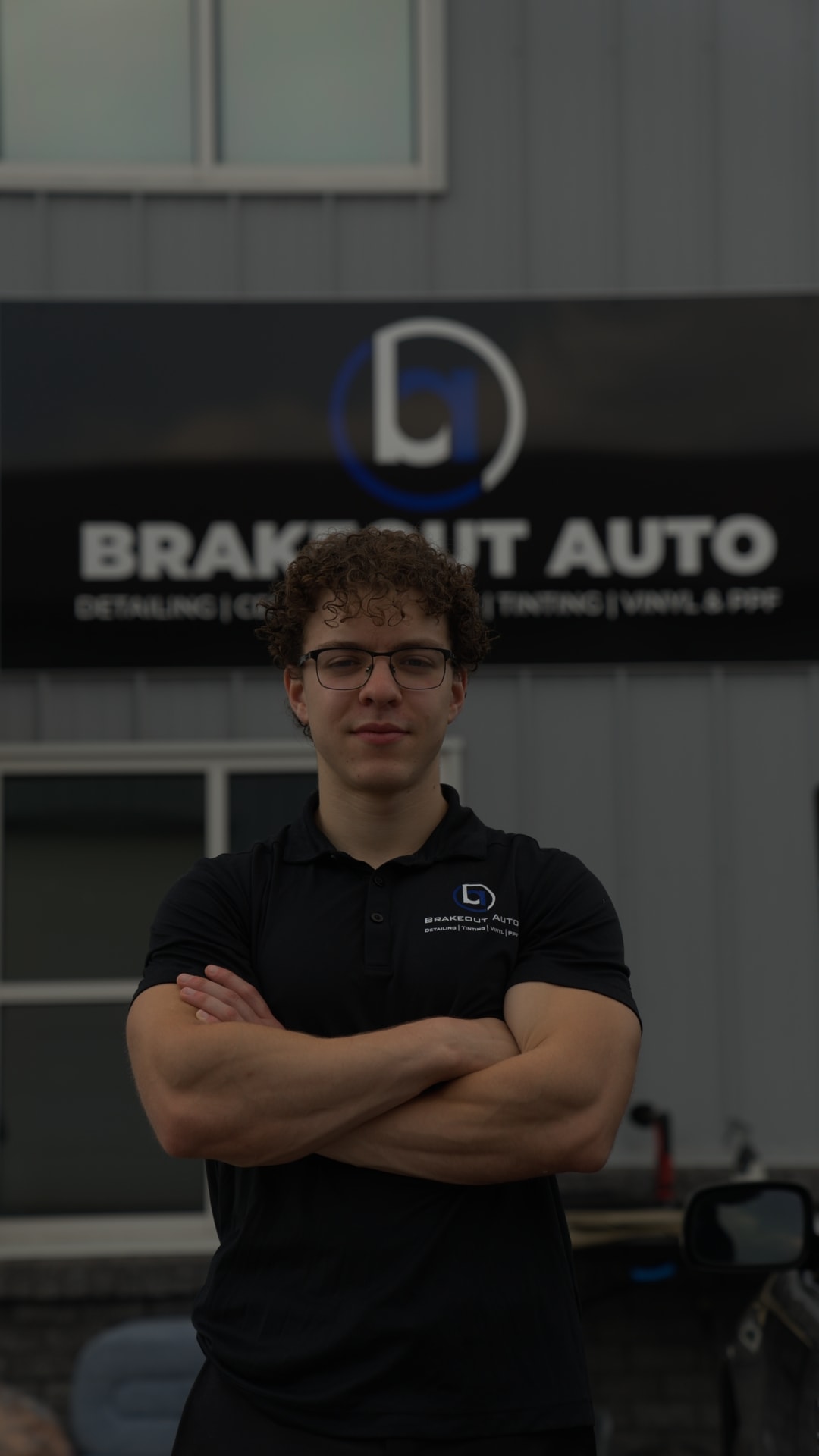 Sullivan Barter, co-founder and owner of Brakeout Auto, standing in front of the Brakeout Auto shop banner in State College, PA.